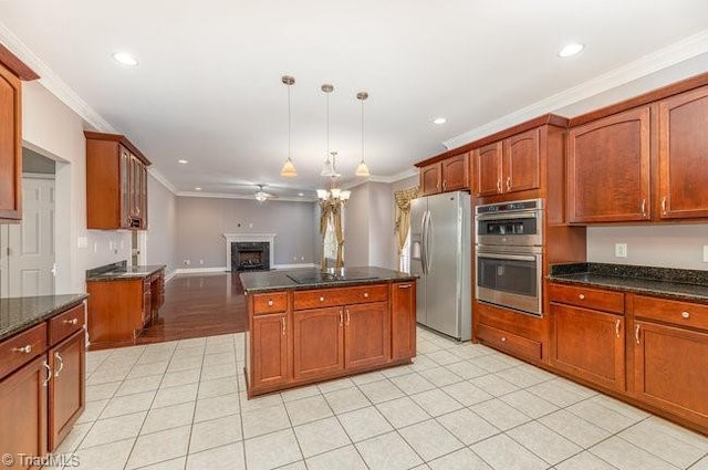 kitchen featuring open floor plan, appliances with stainless steel finishes, a fireplace, and ornamental molding