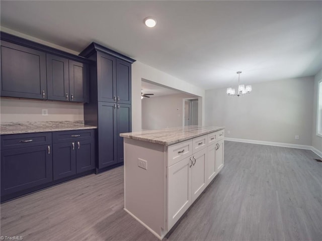 kitchen featuring light hardwood / wood-style floors, white cabinetry, pendant lighting, and light stone countertops