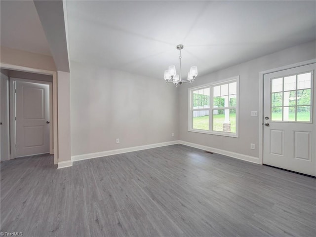 unfurnished dining area with an inviting chandelier and dark hardwood / wood-style flooring