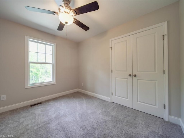 unfurnished bedroom with light colored carpet, ceiling fan, and a closet