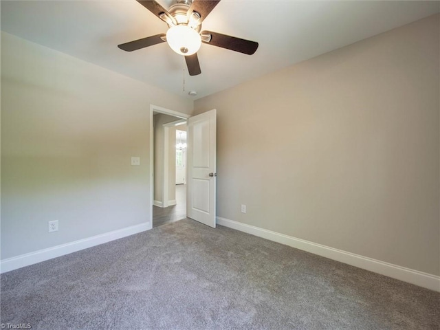 unfurnished room with dark carpet and ceiling fan