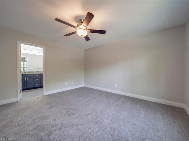 spare room featuring sink, ceiling fan, and light carpet