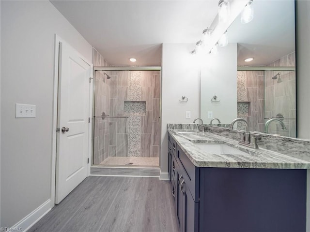 bathroom with a shower with door, hardwood / wood-style floors, and double sink vanity