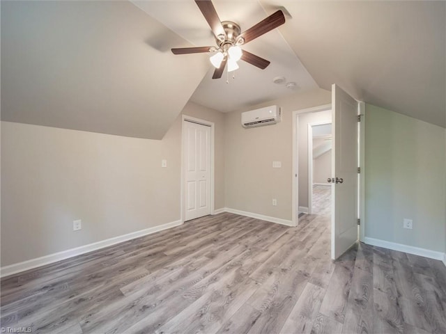 bonus room with ceiling fan, a wall mounted AC, vaulted ceiling, and light wood-type flooring