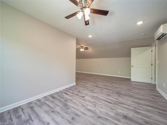 unfurnished room with lofted ceiling, ceiling fan, light wood-type flooring, and a wall unit AC