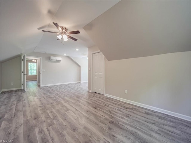 bonus room with a wall unit AC, wood-type flooring, ceiling fan, and lofted ceiling