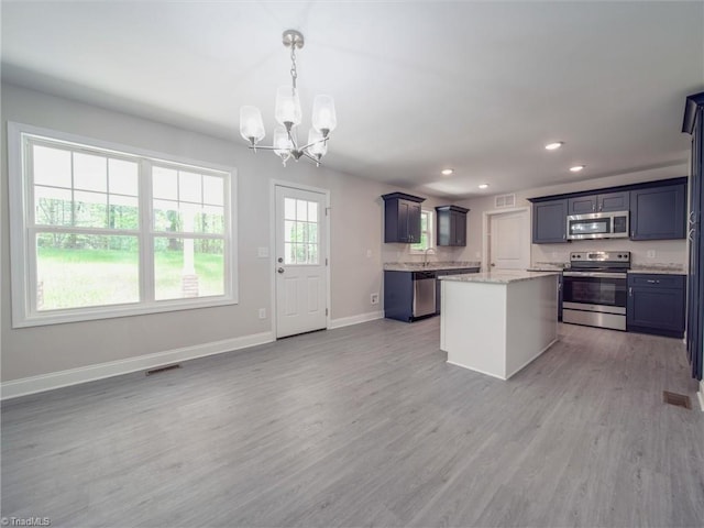 kitchen featuring hanging light fixtures, light hardwood / wood-style flooring, stainless steel appliances, and light stone counters