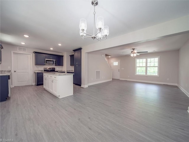 kitchen featuring a kitchen island, ceiling fan with notable chandelier, hardwood / wood-style floors, stainless steel appliances, and pendant lighting