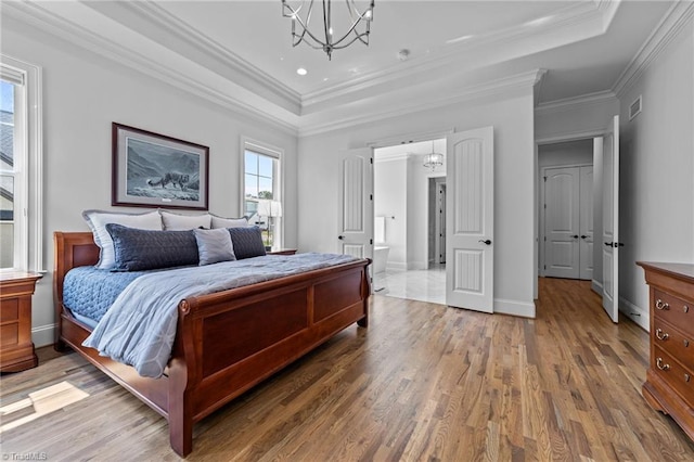 7604 Pemberley Dr, Oak Ridge, NC 27310 - bedroom with a chandelier, a raised ceiling, light wood-style floors, ornamental molding, and connected bathroom