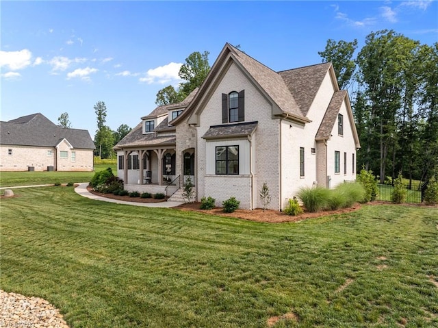 7604 Pemberley Dr, Oak Ridge, NC 27310 - view of front facade with covered porch, a front yard, brick siding, and a shingled roof