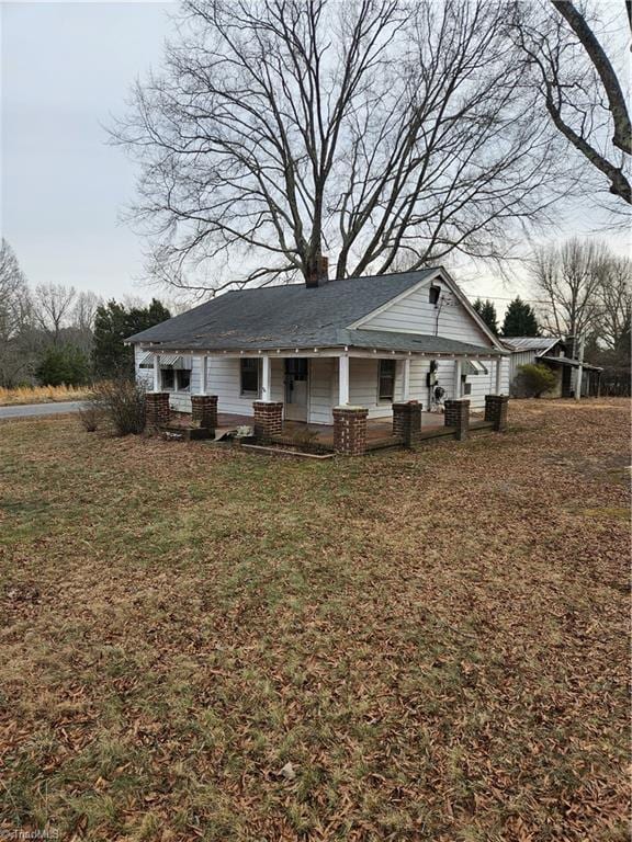 back of property with a yard, a porch, and a chimney