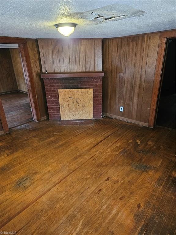 unfurnished living room with wooden walls, dark wood-style floors, and a fireplace