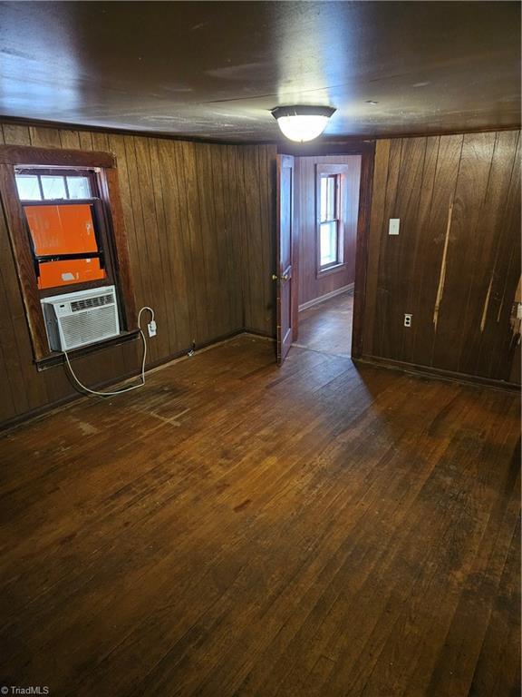 basement with cooling unit, dark wood-style flooring, and wood walls