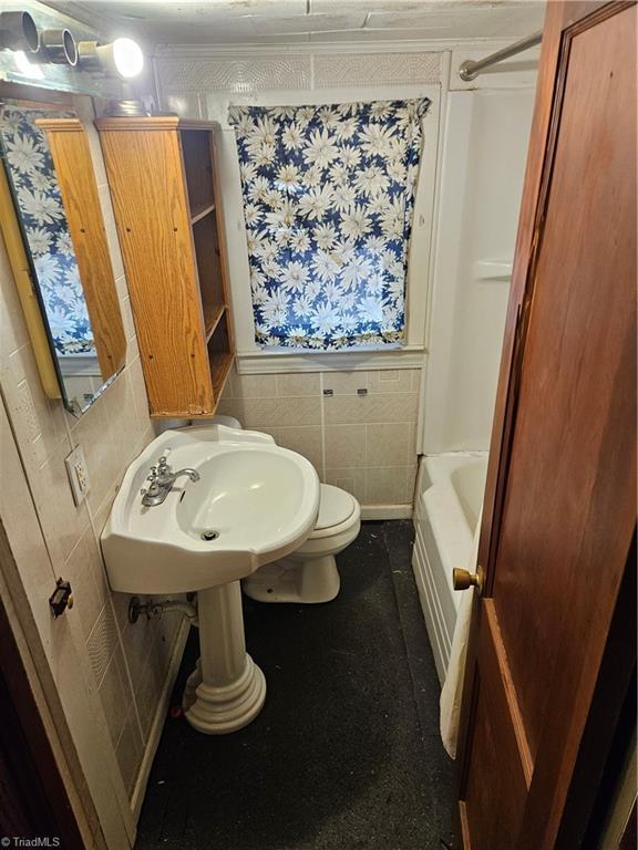 full bath featuring toilet, tile walls, and wainscoting