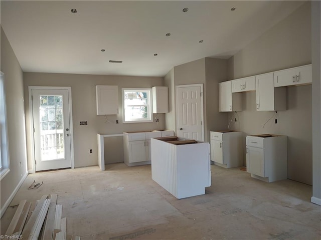 kitchen with white cabinets, vaulted ceiling, and a kitchen island