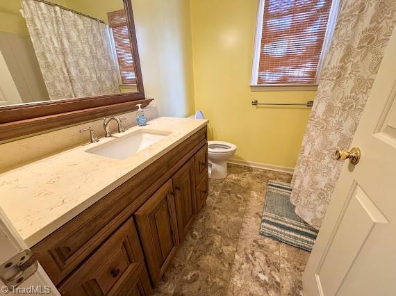 bathroom with toilet, vanity, and baseboards