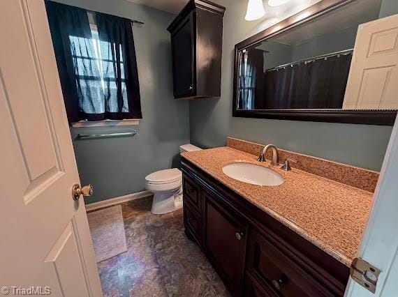 bathroom featuring toilet, baseboards, and vanity