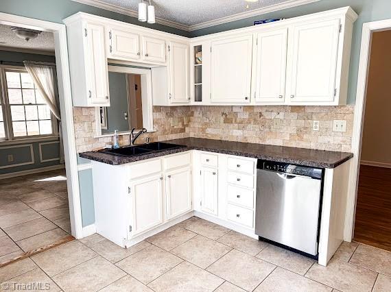 kitchen featuring white cabinets, dark countertops, a textured ceiling, stainless steel dishwasher, and a sink