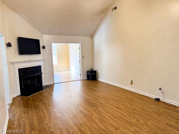 unfurnished living room featuring a fireplace, wood finished floors, visible vents, and baseboards