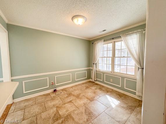 spare room featuring ornamental molding, wainscoting, visible vents, and a decorative wall