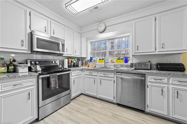 kitchen featuring tasteful backsplash, light wood-style flooring, appliances with stainless steel finishes, and a sink