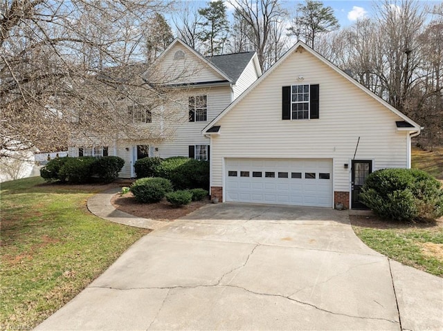 traditional home with an attached garage, concrete driveway, and a front yard