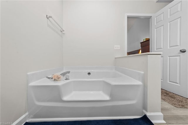 bathroom with a garden tub and baseboards