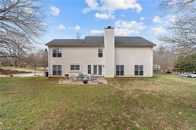 back of house featuring a patio area, a lawn, and a chimney