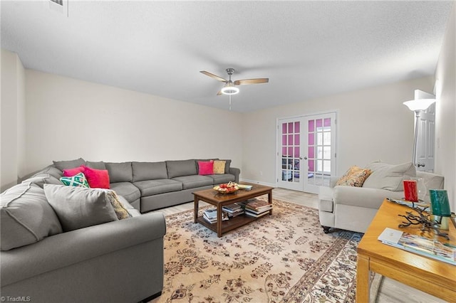 living room featuring a ceiling fan, french doors, light wood-type flooring, and a textured ceiling