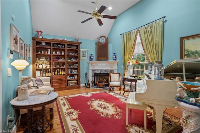 sitting room with wood-type flooring, lofted ceiling, ceiling fan, and a high end fireplace