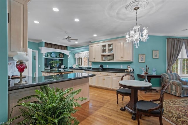 kitchen featuring crown molding, ceiling fan with notable chandelier, pendant lighting, and light hardwood / wood-style flooring