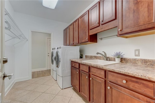 washroom with baseboards, a sink, cabinet space, washing machine and dryer, and light tile patterned flooring