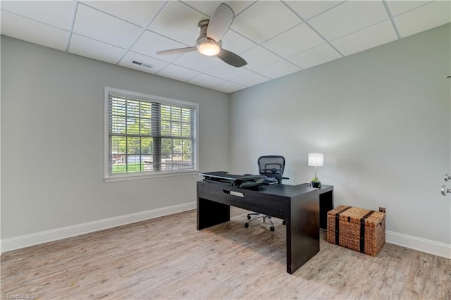 office with a paneled ceiling, baseboards, visible vents, ceiling fan, and wood finished floors