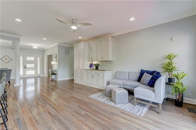 living room with crown molding, ceiling fan, ornate columns, light wood-type flooring, and baseboards