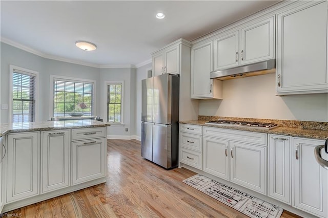 kitchen with ornamental molding, a healthy amount of sunlight, under cabinet range hood, stainless steel appliances, and light wood finished floors