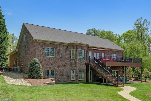 rear view of house featuring brick siding, stairway, a wooden deck, and a lawn