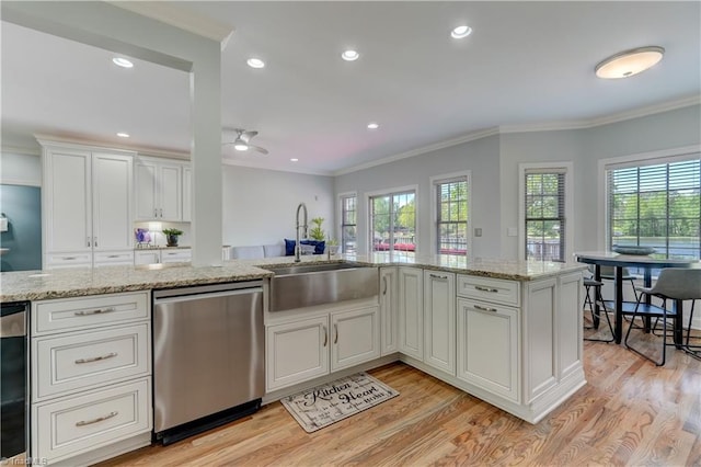 kitchen with light wood finished floors, crown molding, dishwasher, and a sink