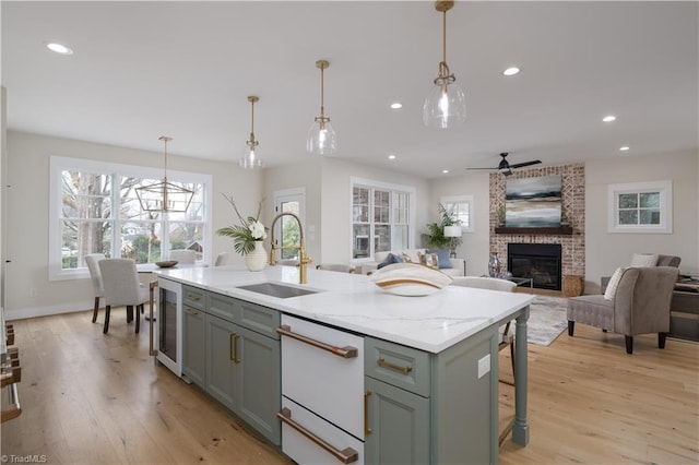 kitchen with a sink, beverage cooler, a fireplace, dishwasher, and plenty of natural light
