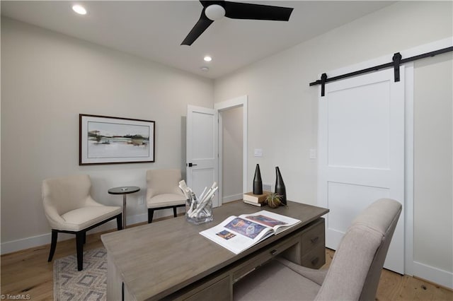 office area featuring ceiling fan, a barn door, light wood-style floors, recessed lighting, and baseboards