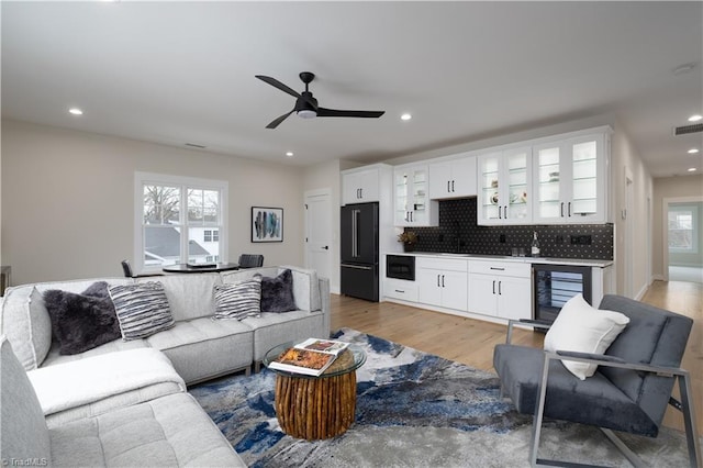 living area with bar area, wine cooler, recessed lighting, ceiling fan, and light wood finished floors