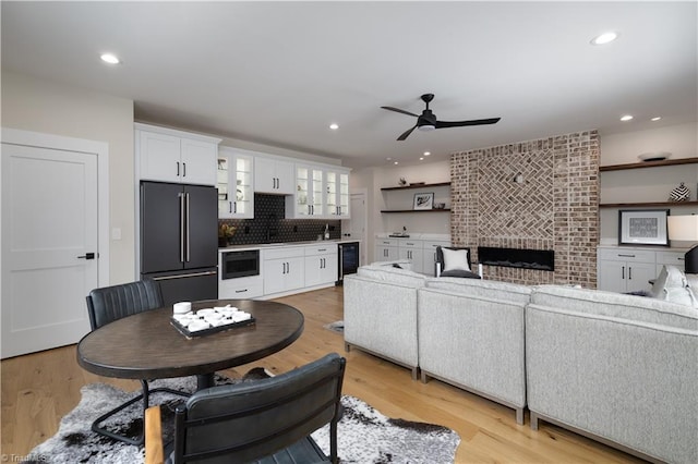 living area featuring a ceiling fan, light wood-style flooring, a brick fireplace, recessed lighting, and wine cooler