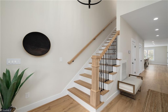 stairway with wood finished floors, recessed lighting, and baseboards