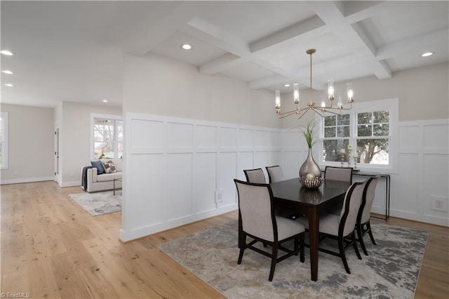 dining space featuring a decorative wall, coffered ceiling, a chandelier, plenty of natural light, and beam ceiling