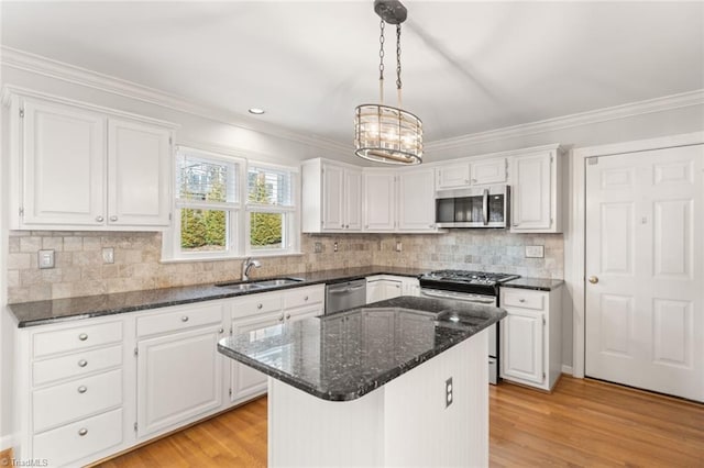 kitchen with sink, white cabinetry, a center island, dark stone counters, and stainless steel appliances