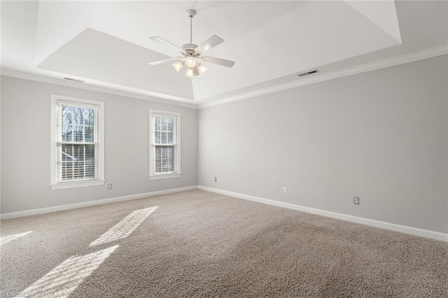 carpeted empty room with ceiling fan, ornamental molding, and a raised ceiling