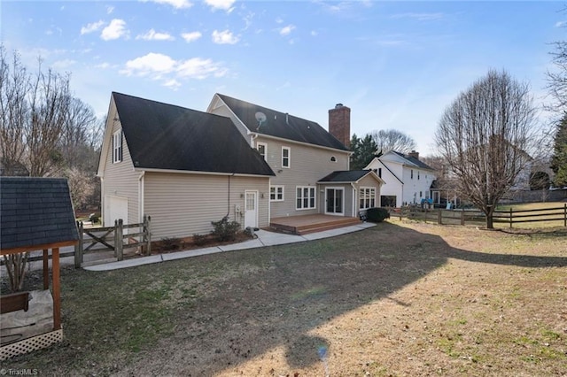 back of property featuring a wooden deck, a garage, and a lawn