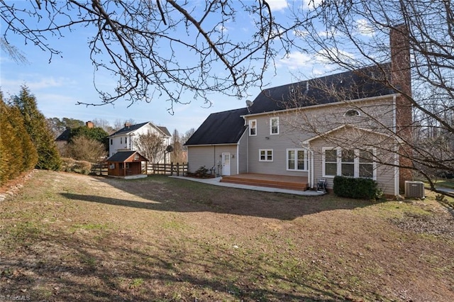 rear view of house featuring central AC unit, a lawn, and a deck