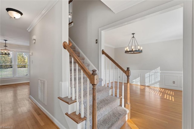 stairway featuring a notable chandelier, crown molding, and hardwood / wood-style floors