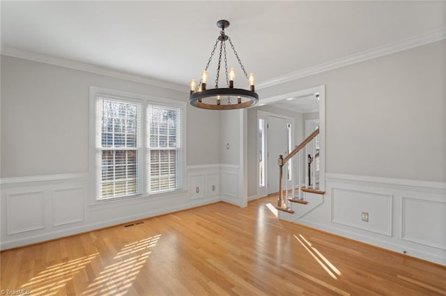 unfurnished dining area featuring an inviting chandelier, ornamental molding, and light hardwood / wood-style floors