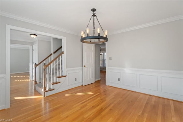 empty room with an inviting chandelier, wood-type flooring, and crown molding